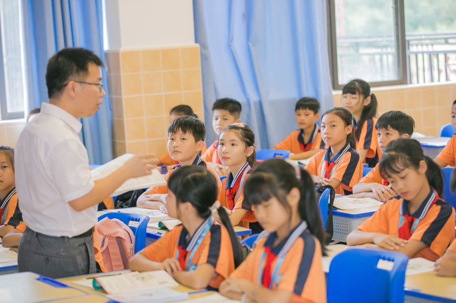 Seorang guru membimbing kanak-kanak semasa pembelajaran di bilik darjah.
